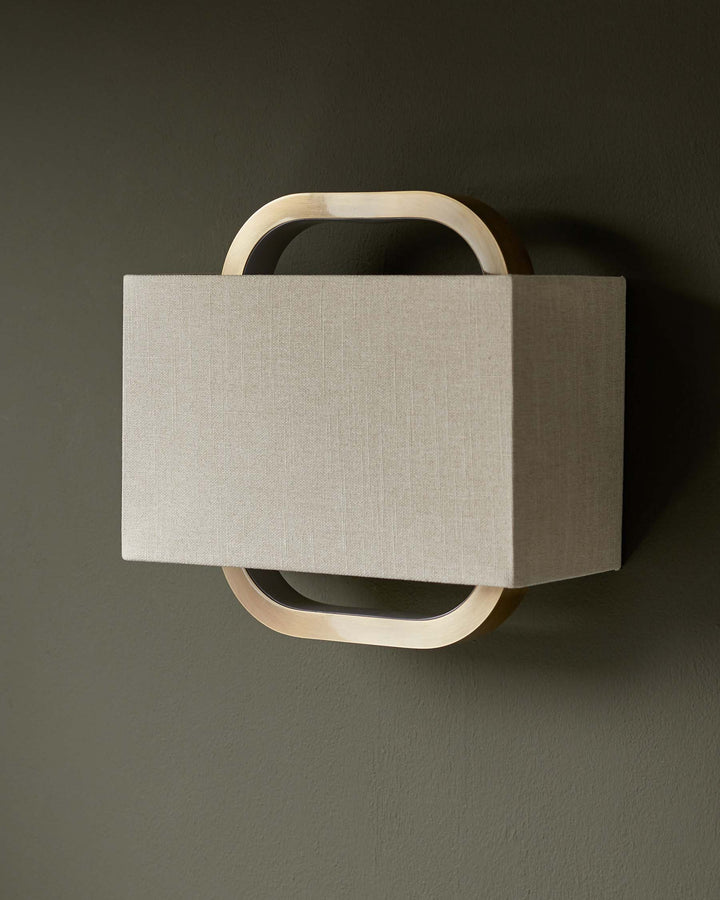 Contemporary wall light with a rectangular shade, framed by curved metallic supports for a stylish, modern look.
