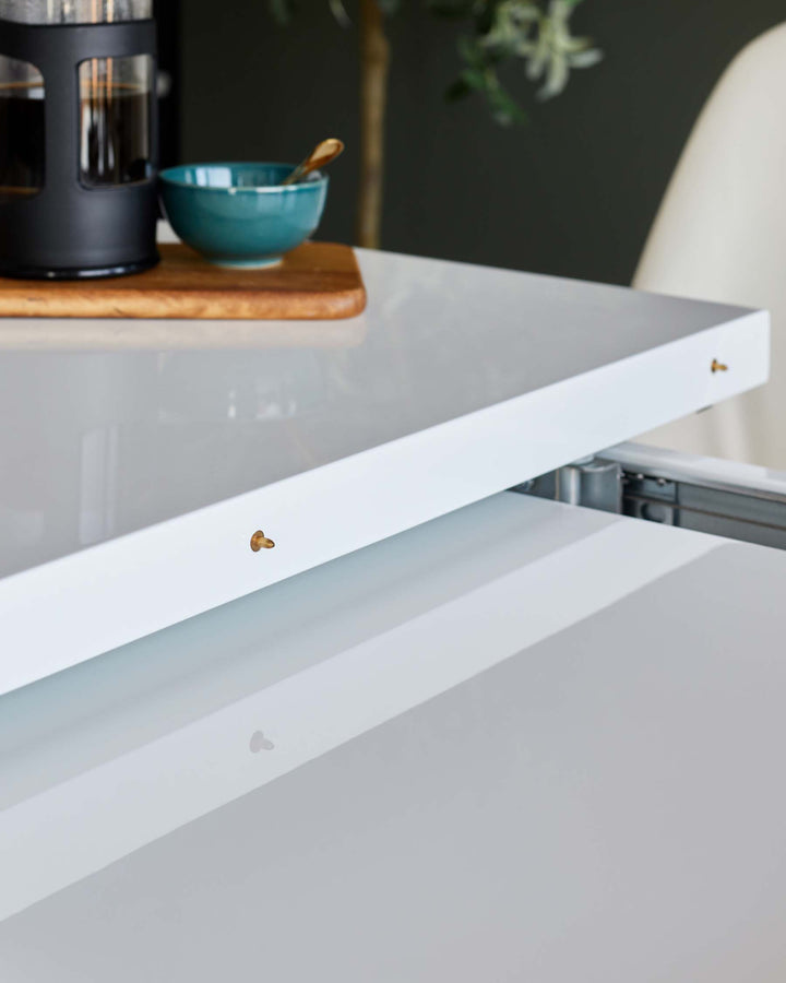 A modern white extending dining table with a sleek, glossy finish, perfect for contemporary dining spaces.