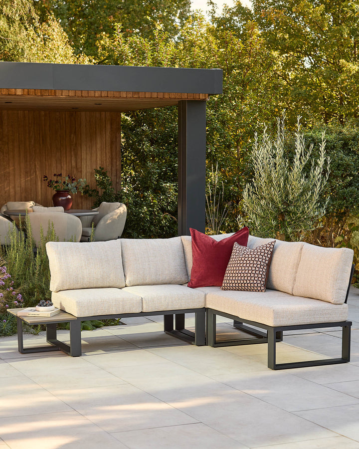 Savannah garden large corner black base bench with natural cushions, styled in a contemporary outdoor patio setting with decorative pillows.