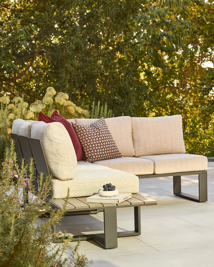 Savannah garden large corner bench with black metal base and natural cushions, styled in an outdoor setting with plants.