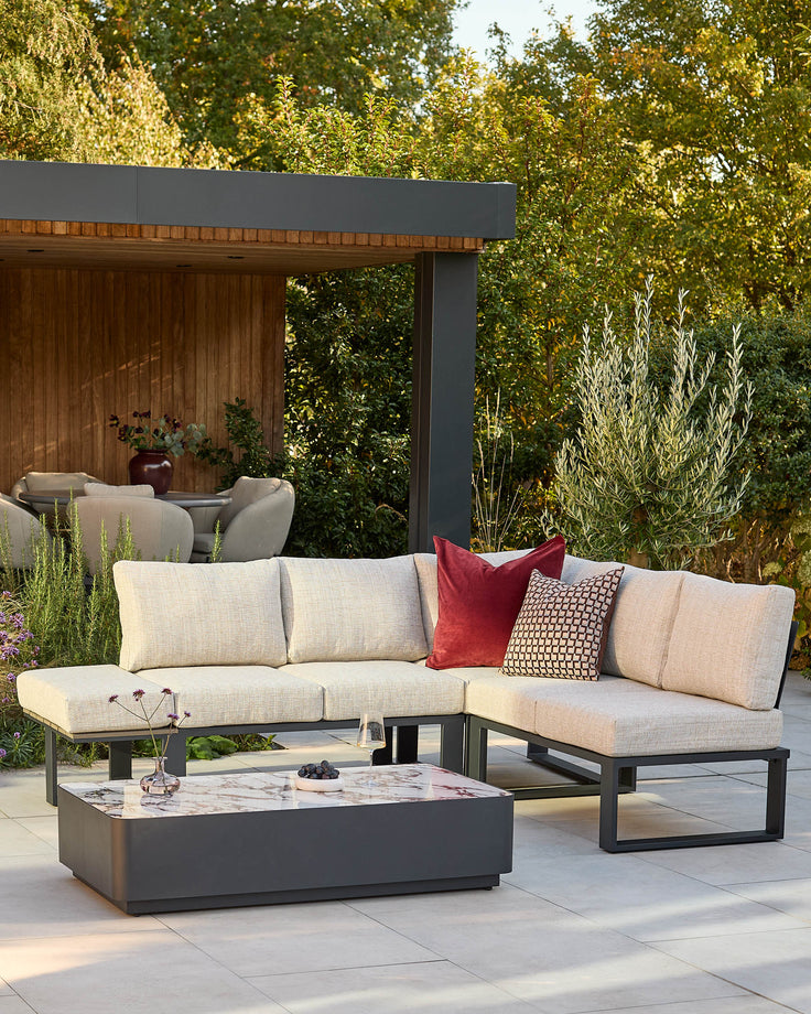 Savannah garden large corner bench set with black base, natural cushions, and marble coffee table in outdoor patio setting.