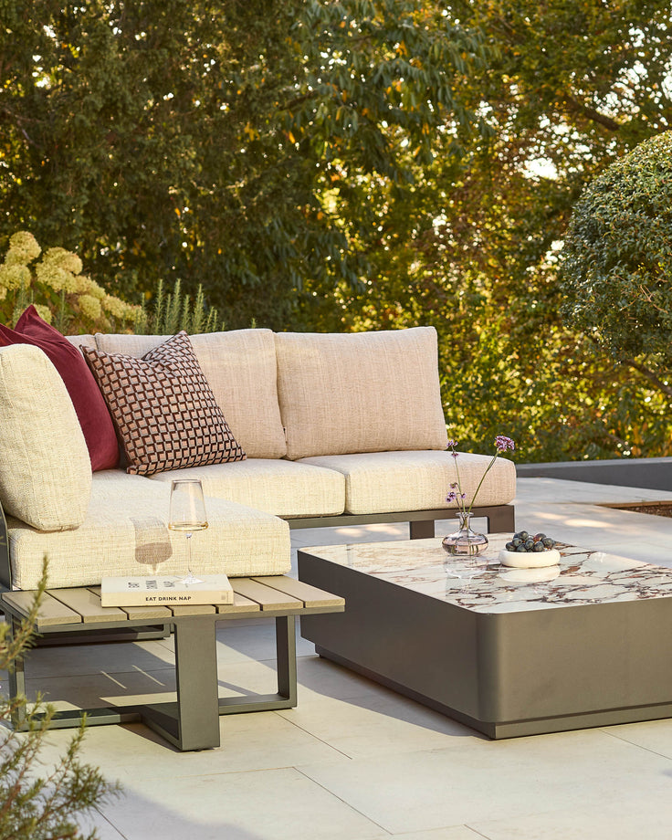 Savannah garden corner bench set with cream cushions, patterned pillows, and bianco coffee table in natural outdoor setting.