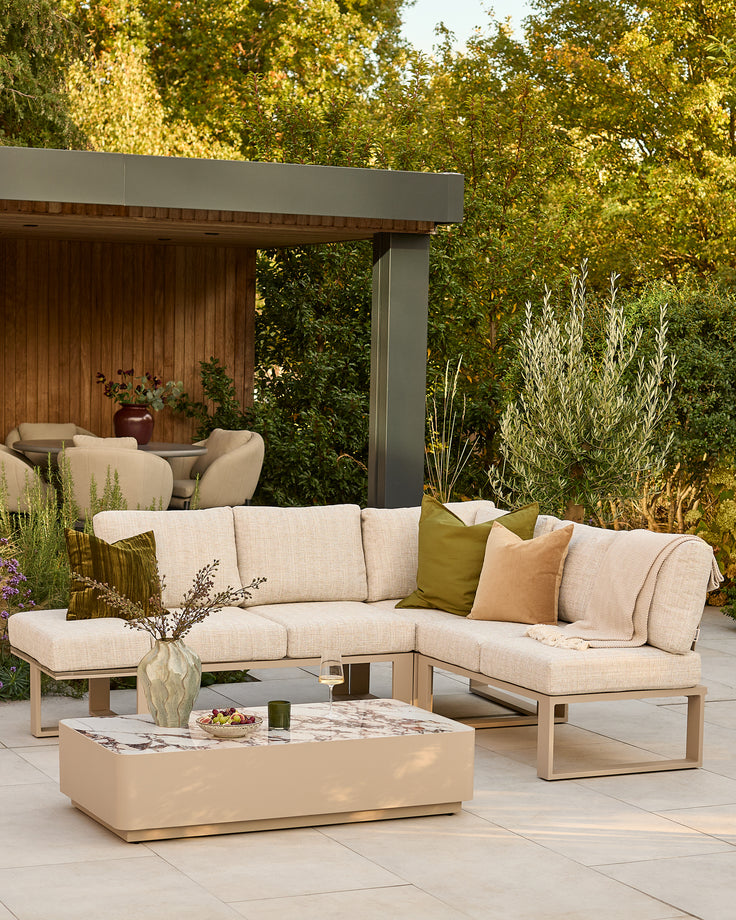 Savannah large corner garden sofa set in natural with beige cushions and matching coffee table in outdoor setting.