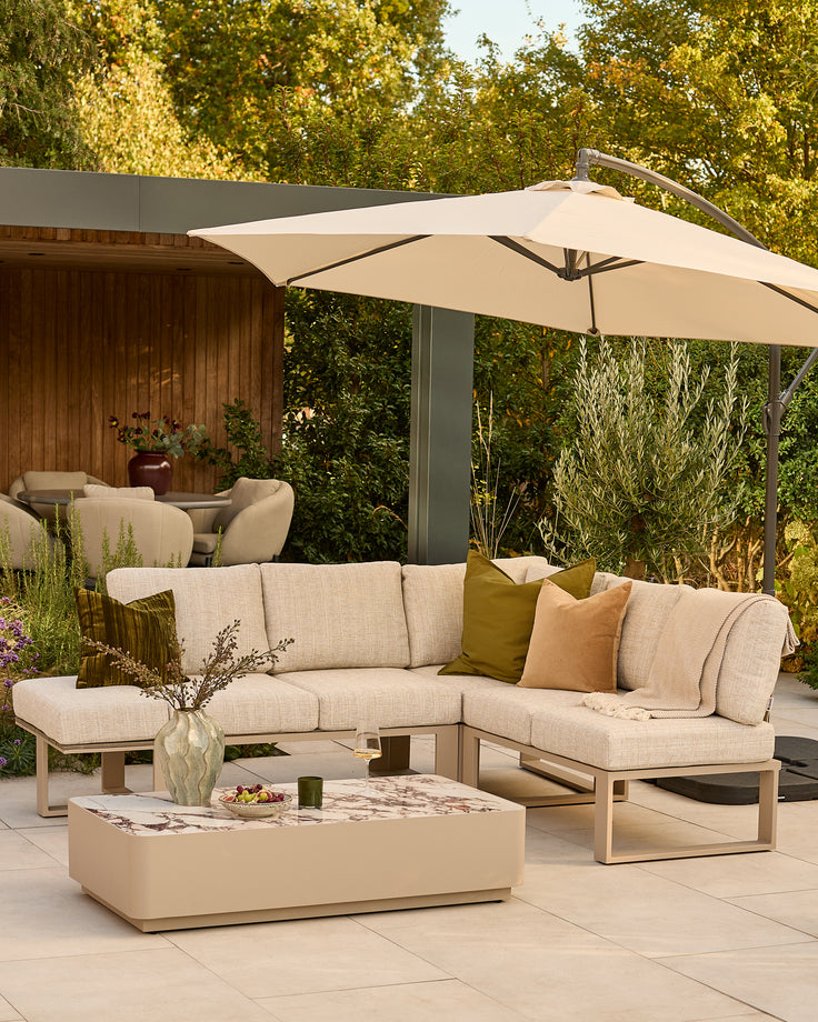 Savannah garden large corner sofa set in natural with beige cushions, bench seat, bianco coffee table, and cantilever umbrella.