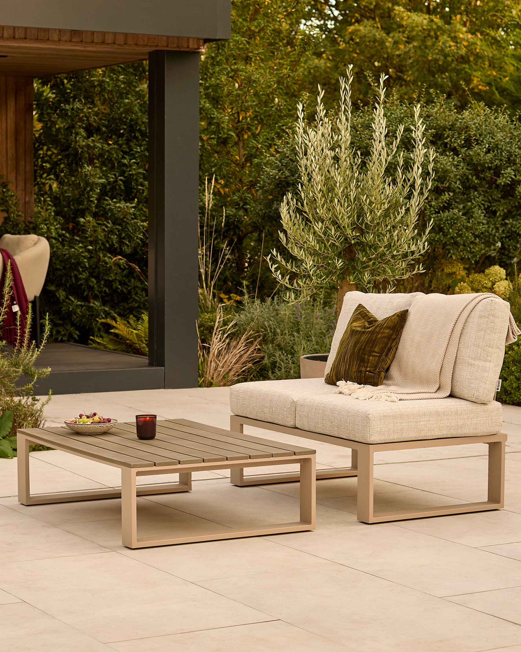 Savannah natural wood daybed set with cream cushions and olive throw pillow on a patio, paired with a matching coffee table.