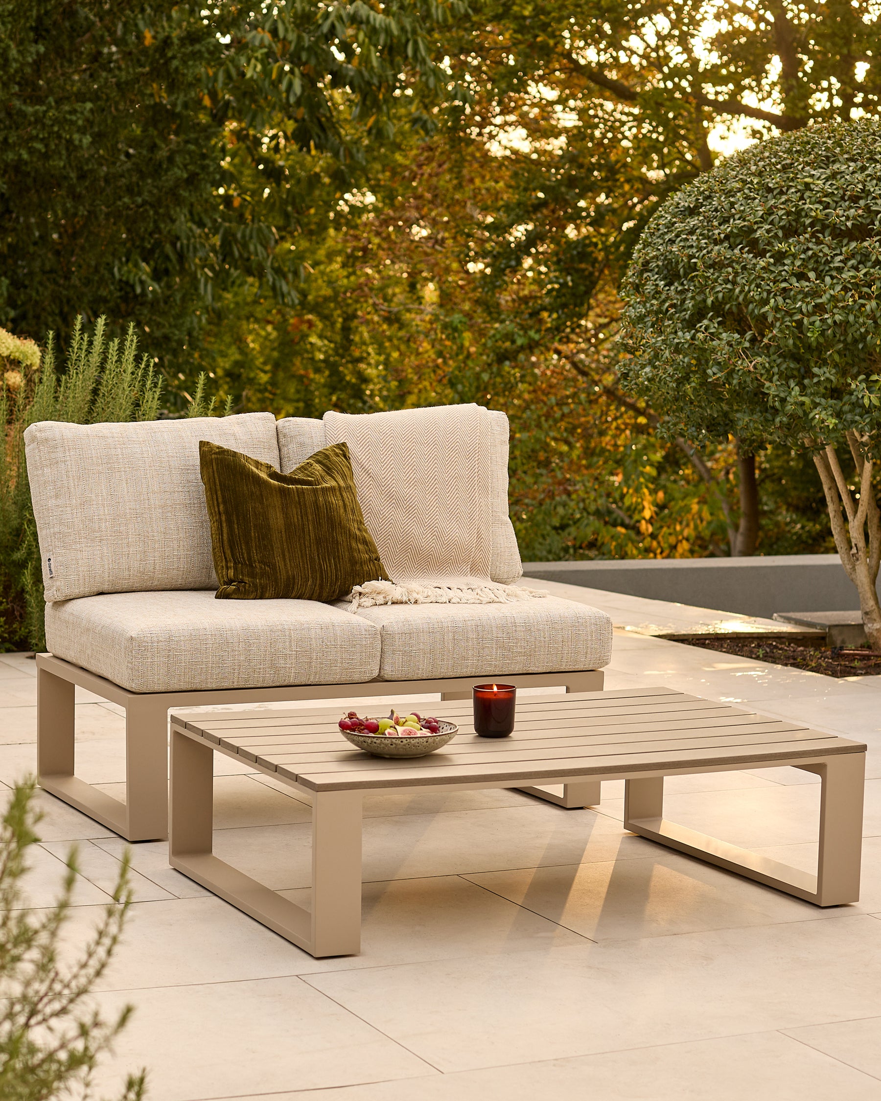 Savannah garden daybed set in natural finish with beige cushions and olive pillow, paired with matching coffee table in outdoor setting.