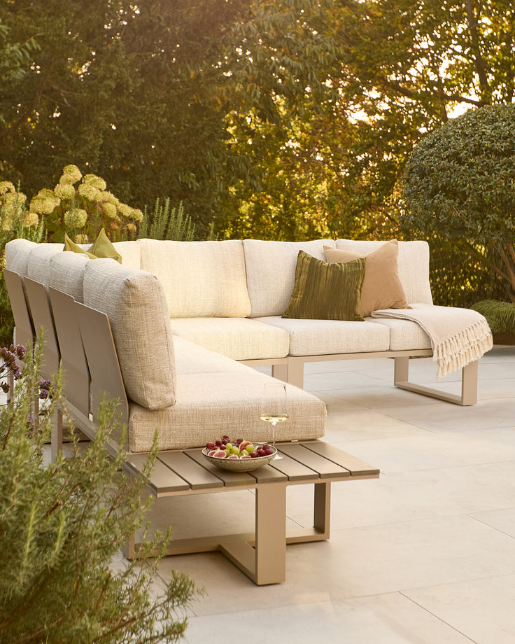 Savannah garden extra-large corner sofa in natural with wooden base, styled with cushions in a lush garden setting.