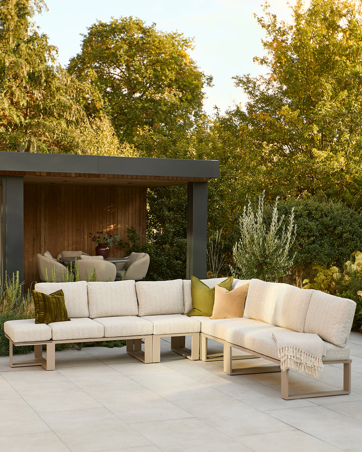 Savannah garden extra-large corner sectional with natural wood base and cream cushions, styled on a patio with accent pillows.