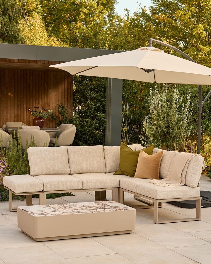 Savannah large corner garden sofa set in natural with beige cushions, coffee table, and cantilever umbrella in outdoor setting.