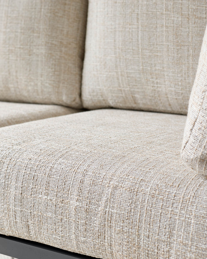 Beige linen upholstered corner bench with black base, close-up detail of seat cushion texture.