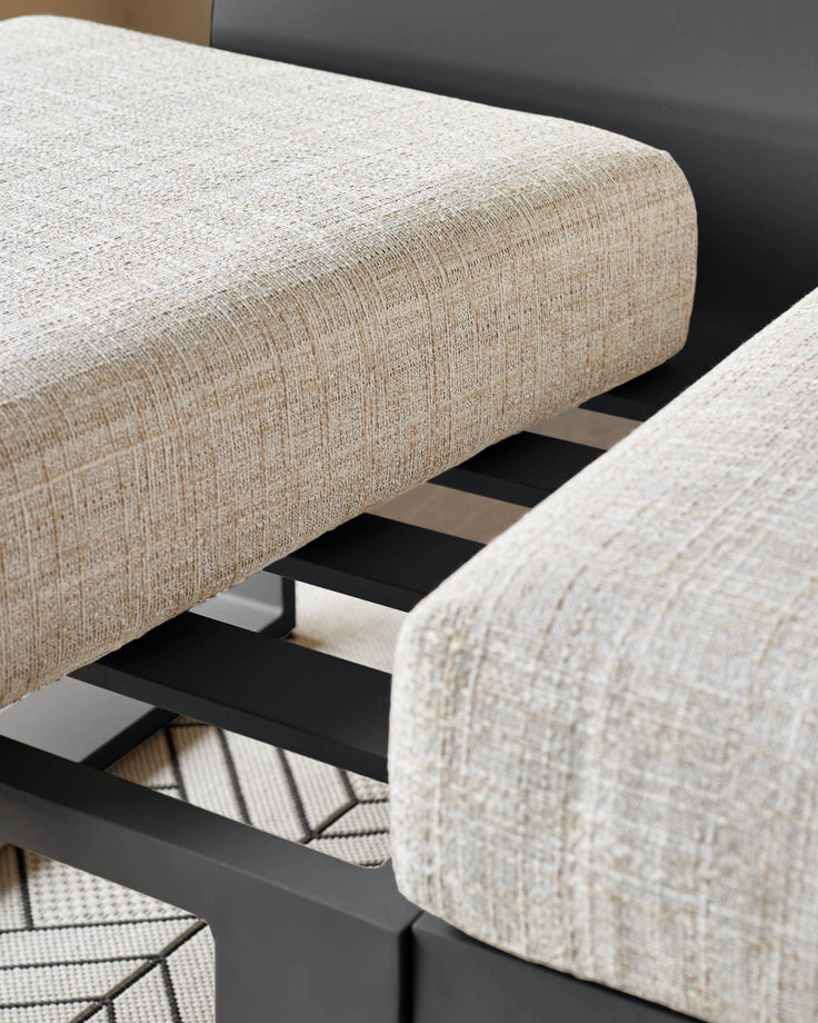 Savannah garden bench with natural linen upholstery and black metal base, angled side view showing curved armrests.
