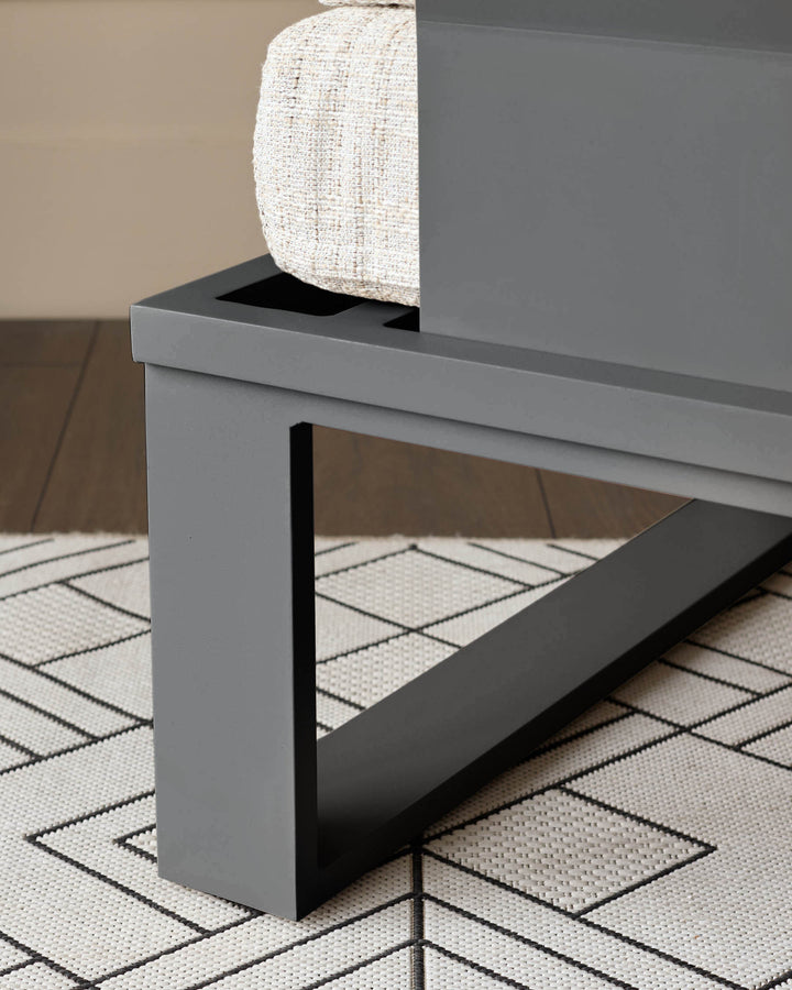 Savannah garden large corner bench with black base and natural cushion, side view on patterned rug.