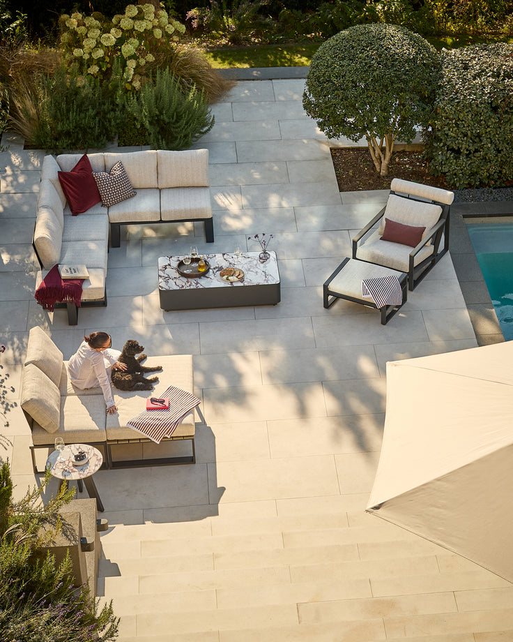 Savannah garden extra large corner bench in natural, shown in a modern patio setting with coordinating outdoor furniture.