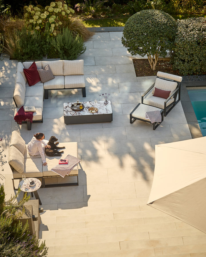 Savannah garden large corner bench set in natural base with bianco coffee table, styled on a patio with cushions and decor.