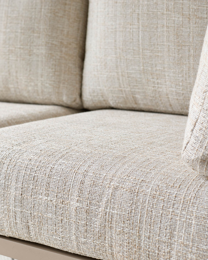 Beige linen upholstered corner sofa close-up showing textured fabric, cushions, and seat detail.