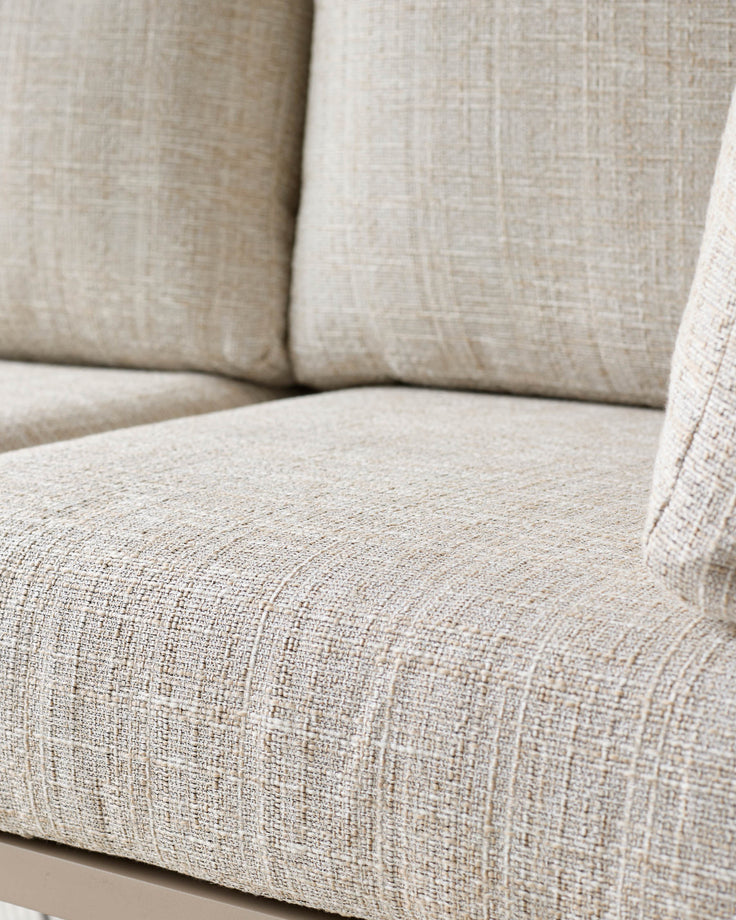 Beige linen upholstered corner sofa close-up showing textured fabric, cushions, and seat detail.