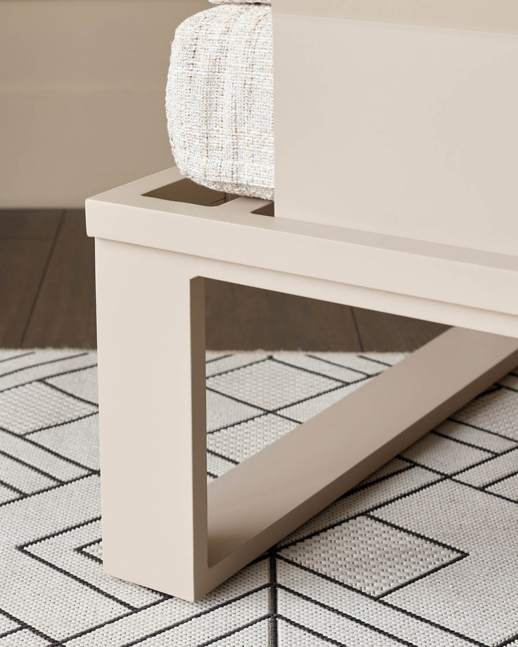 White modern bench with open storage compartment, cream textured cushion, paired with geometric patterned rug.