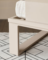 White wooden corner bench with cream upholstered backrest, shown from side angle on patterned rug.