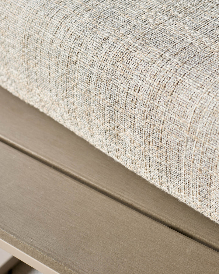 Cream upholstered corner bench with natural wood base, shown at close-up angle highlighting textured fabric detail.