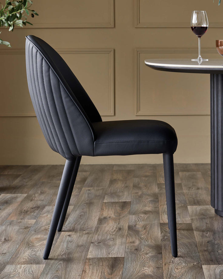 A stylish black dining chair sits next to a round table, perfect for a modern dining space.