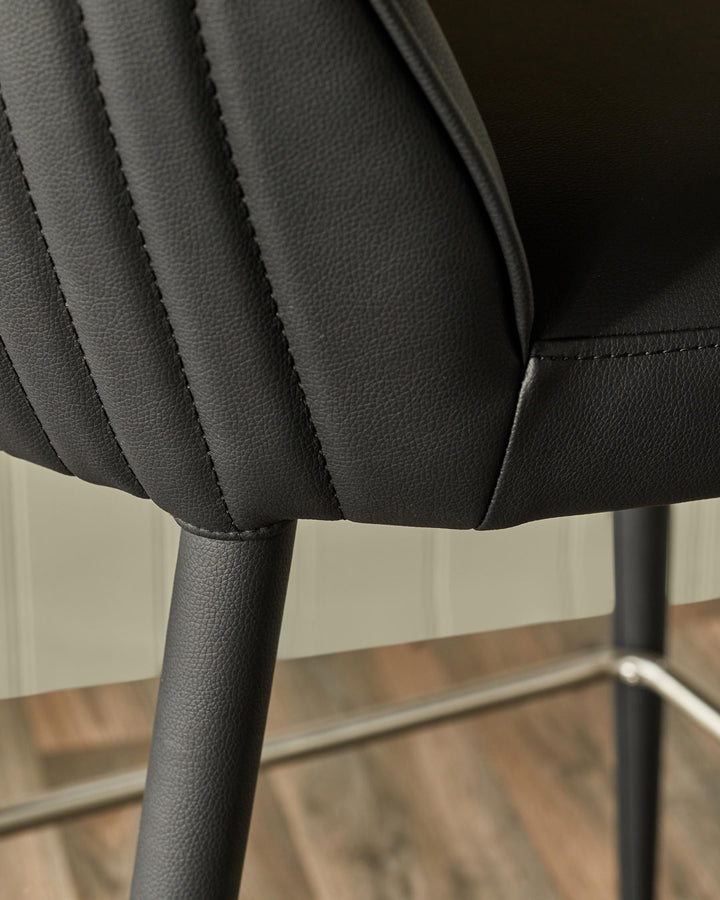 Close-up of a stylish black faux leather bar stool with a quilted backrest and sleek metal accents.