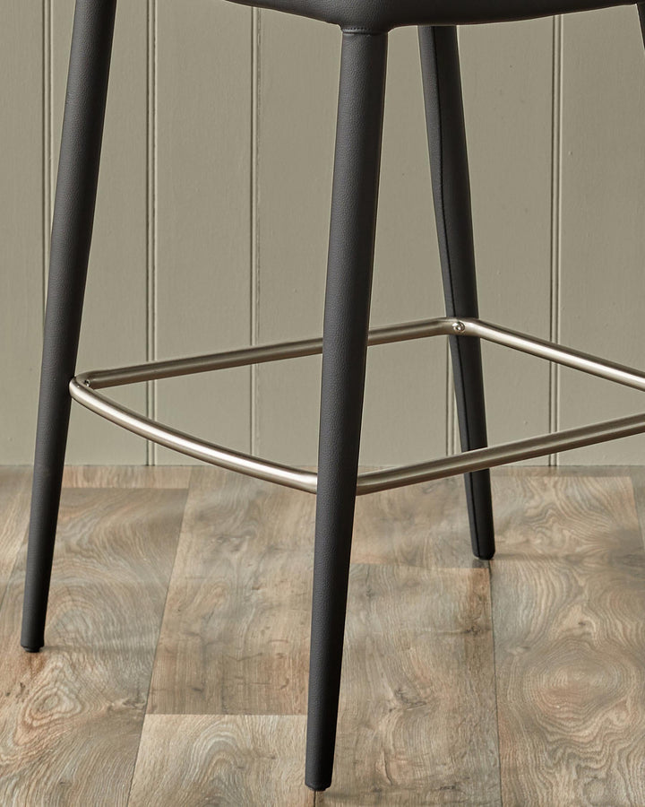 Close-up of a modern black bar stool with a silver footrest and a wood-effect floor.