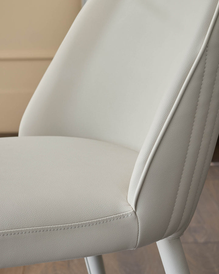 Saylor faux-leather dining chair in light grey, shown from side angle highlighting textured seat and backrest stitching details.