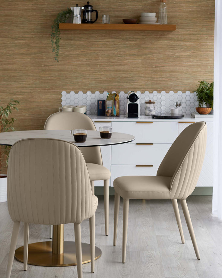 Contemporary dining setting with round table, gold base, and three stylish, upholstered chairs.
