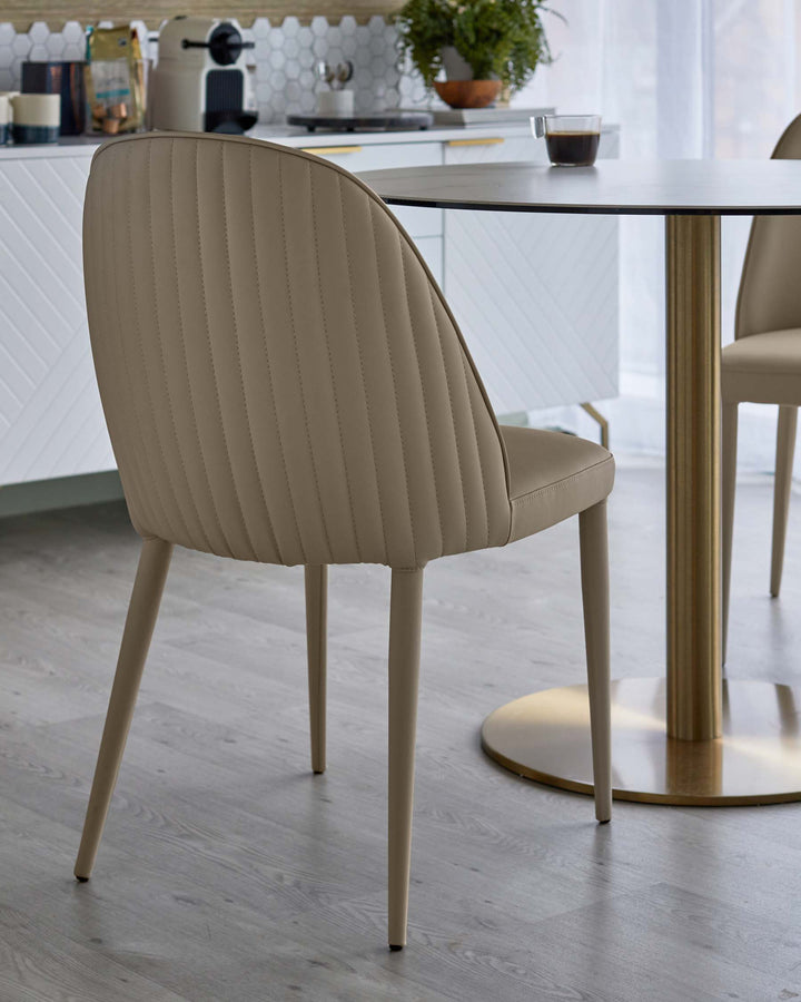 A contemporary dining room featuring upholstered chairs and a round table with a gold pedestal base.