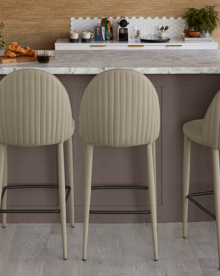 Three stylish upholstered bar stools with rounded backs, set at a kitchen island, offering comfortable seating.