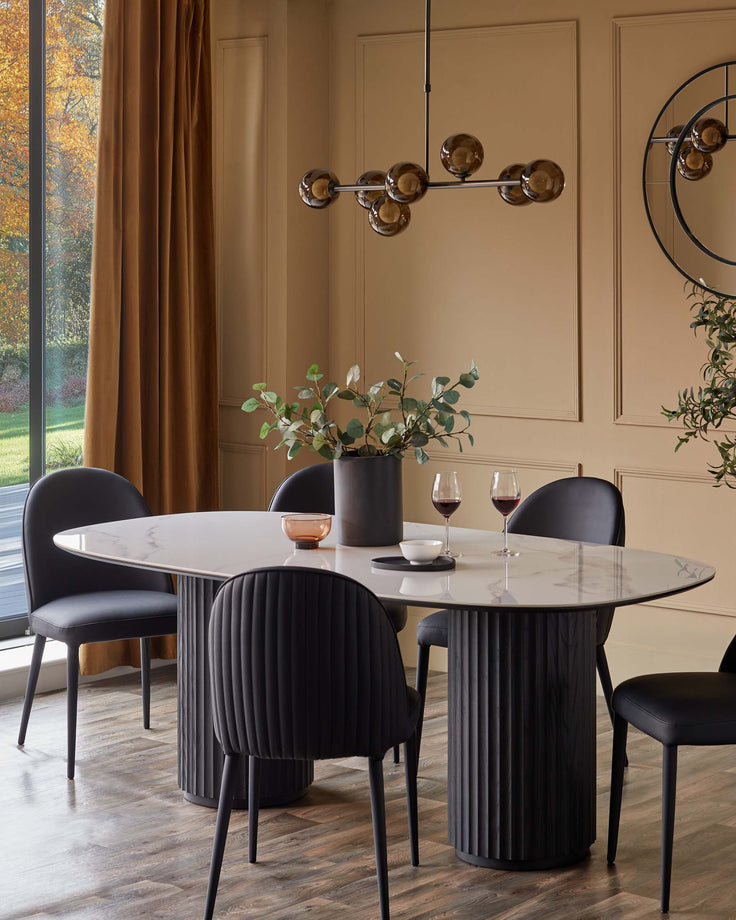A dining room with a marble table and six black chairs under a modern chandelier.