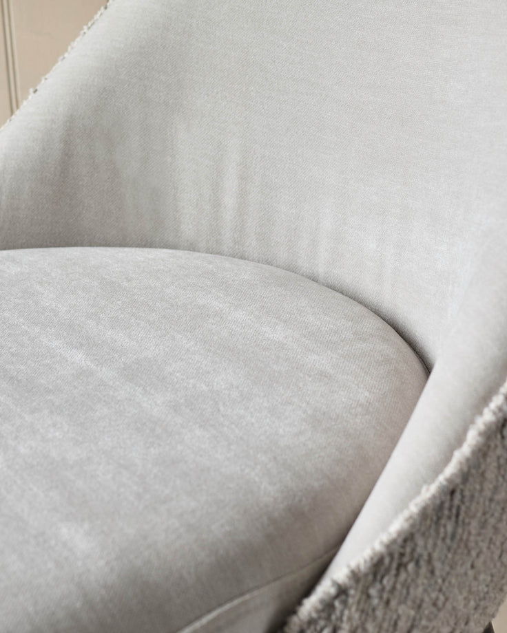 Close-up of a light grey upholstered chair, showing the seat and backrest. Soft, textured fabric for a cosy feel.