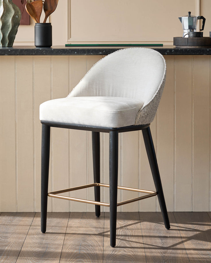 A contemporary bar stool with black legs, gold footrest and a stylish white upholstered seat.