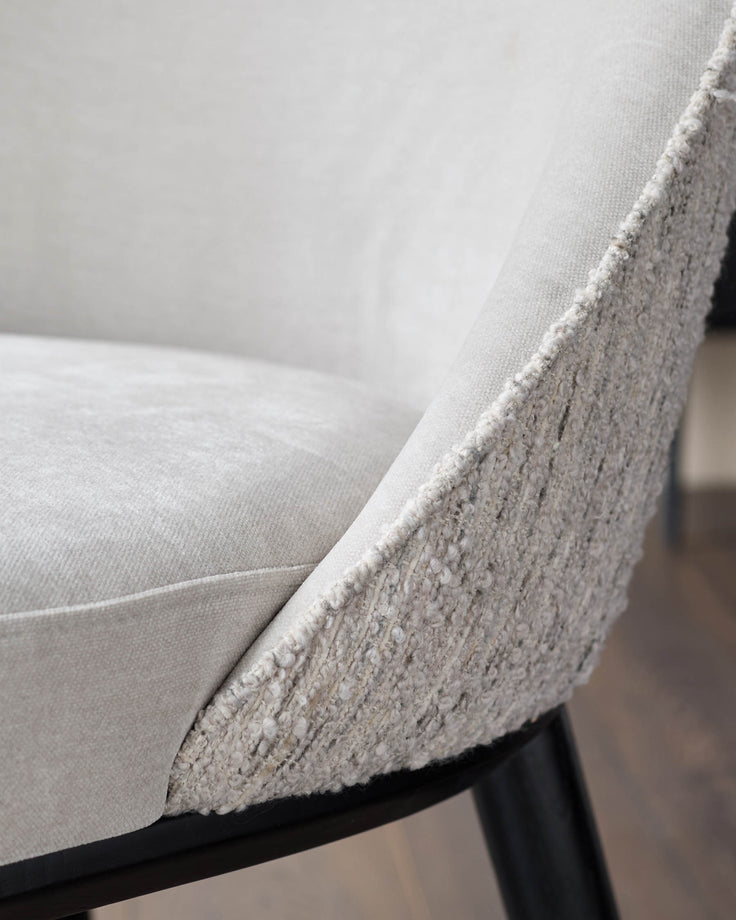 Close-up of a stylish chair with textured fabric and dark wooden legs, showcasing comfort and modern design.