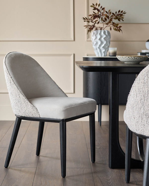 A dining set with upholstered chairs and a dark wood table with a decorative vase and ornaments.