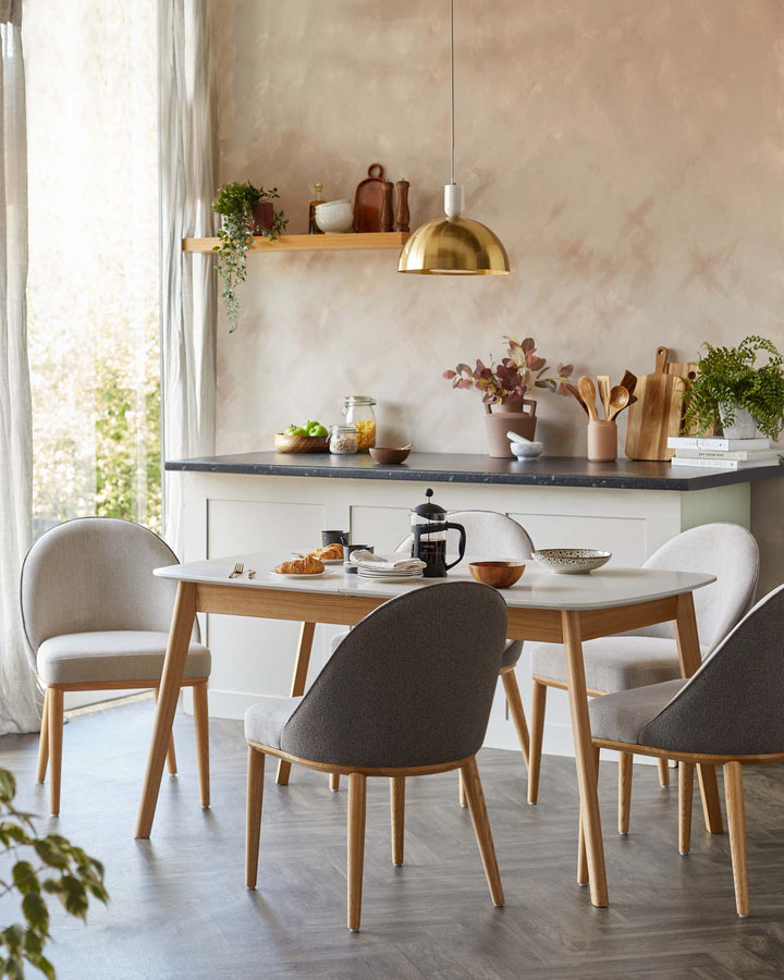 Dining set featuring an oval table with four chairs. Modern design with light wood and grey upholstery.