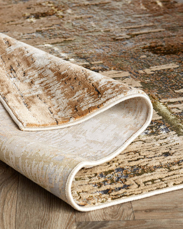 A patterned area rug is partially rolled, showcasing the underside and binding detail on a wooden floor.
