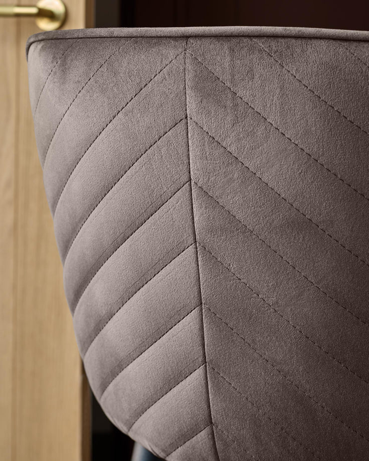 Serena mocha velvet bar stool with quilted chevron stitching detail, shown in close-up side view.
