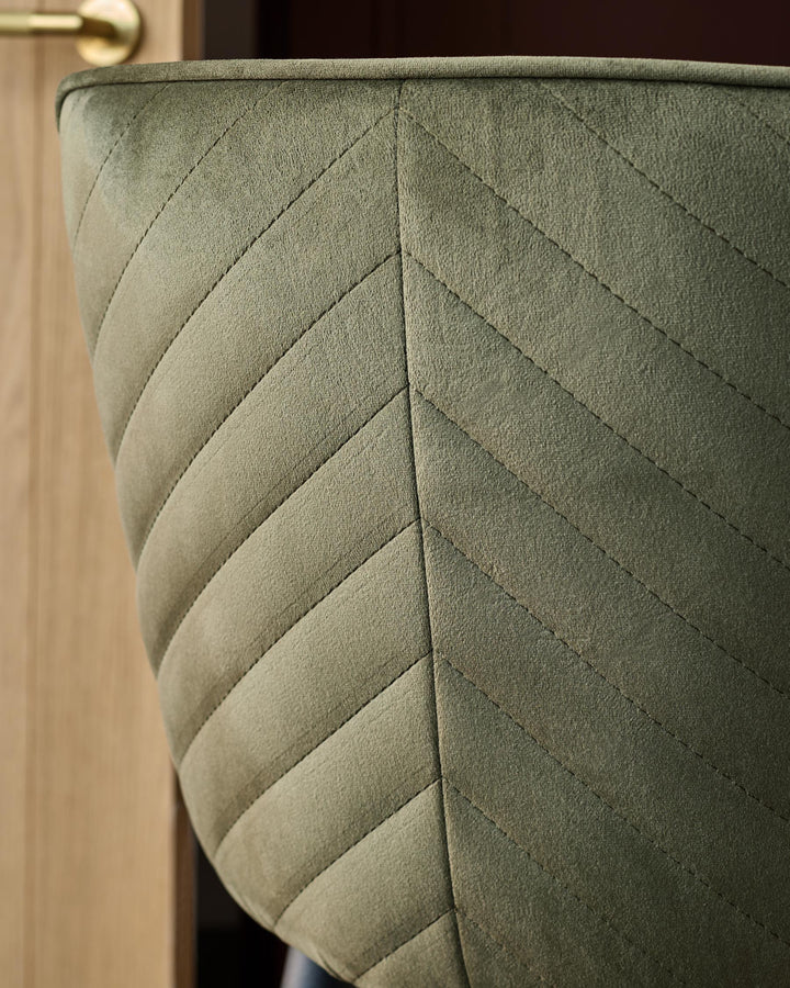 Close-up of a green upholstered chair with a herringbone pattern, showcasing its texture and design in detail.