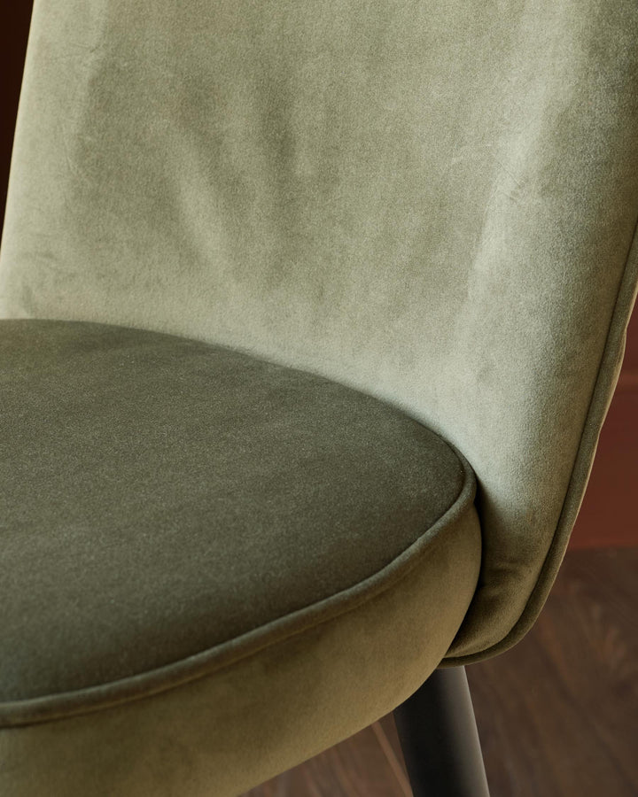 Olive green velvet dining chair with a curved back and seat, showcasing an elegant and comfortable design.