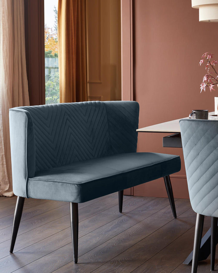 A modern blue velvet dining bench with dark wooden legs, complementing a chair with matching upholstery.