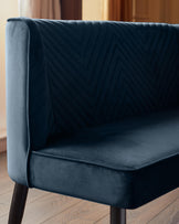 Close-up of a navy blue settee with a chevron design. The settee has dark wooden legs and is upholstered in velvet.