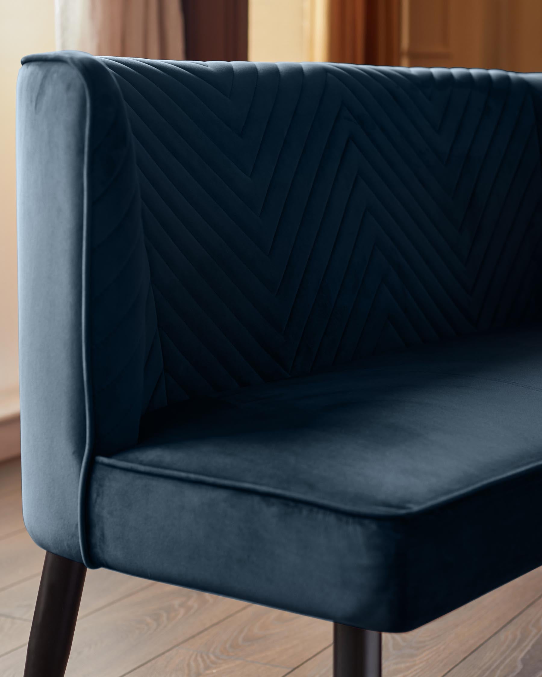 Close-up of a navy blue settee with a chevron design. The settee has dark wooden legs and is upholstered in velvet.