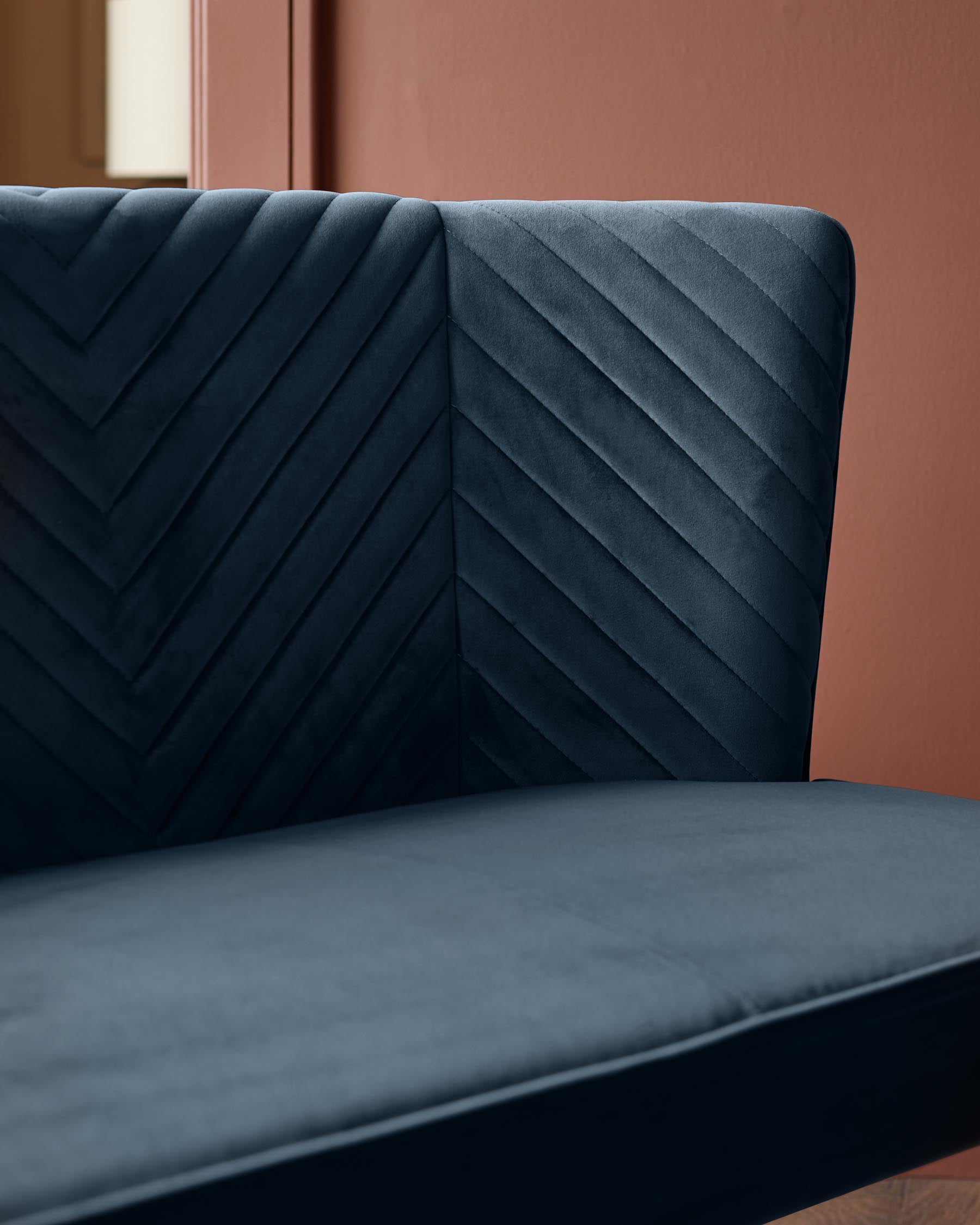 Close-up of a blue velvet chair with a stylish quilted back, perfect for adding a touch of luxury to any room.