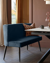 A stylish navy blue velvet bench seat with a geometric cushion, complemented by a modern dining table.