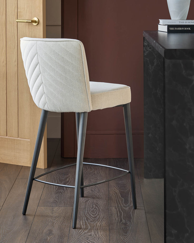 Upholstered bar stool in pale fabric with patterned back and dark grey metal legs.