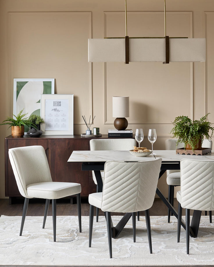 A stylish dining set featuring a marble table, upholstered chairs with black legs, and a modern linear light fixture.