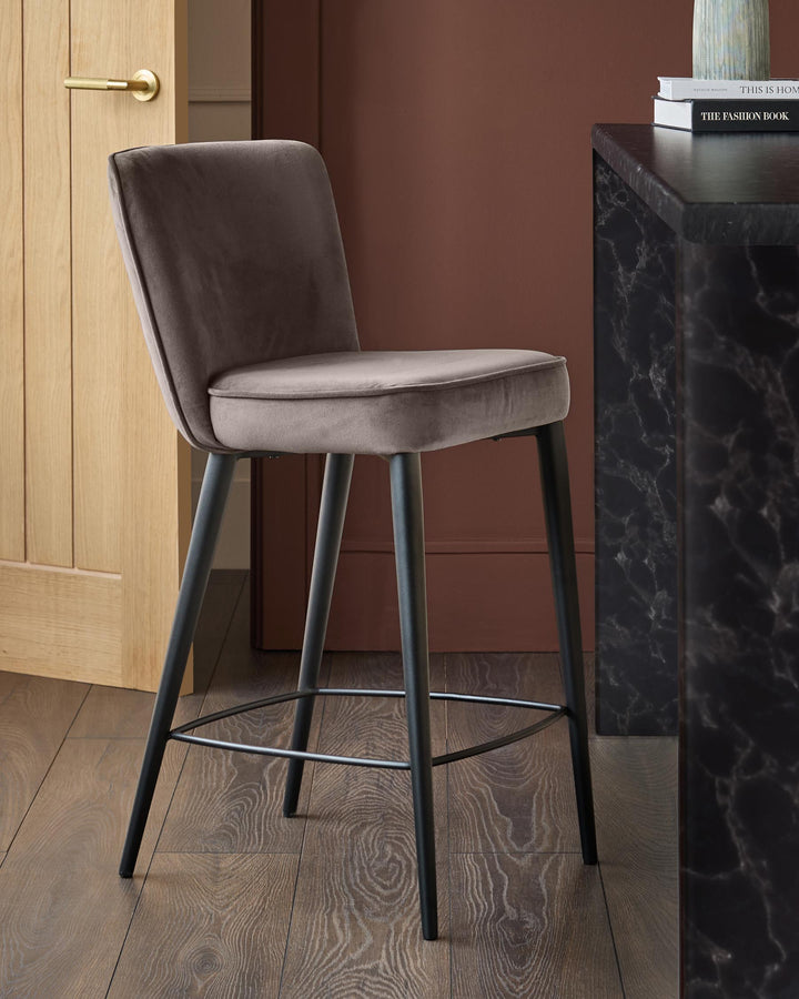 Serena mocha velvet bar stool with black legs and footrest, angled view in styled room setting.
