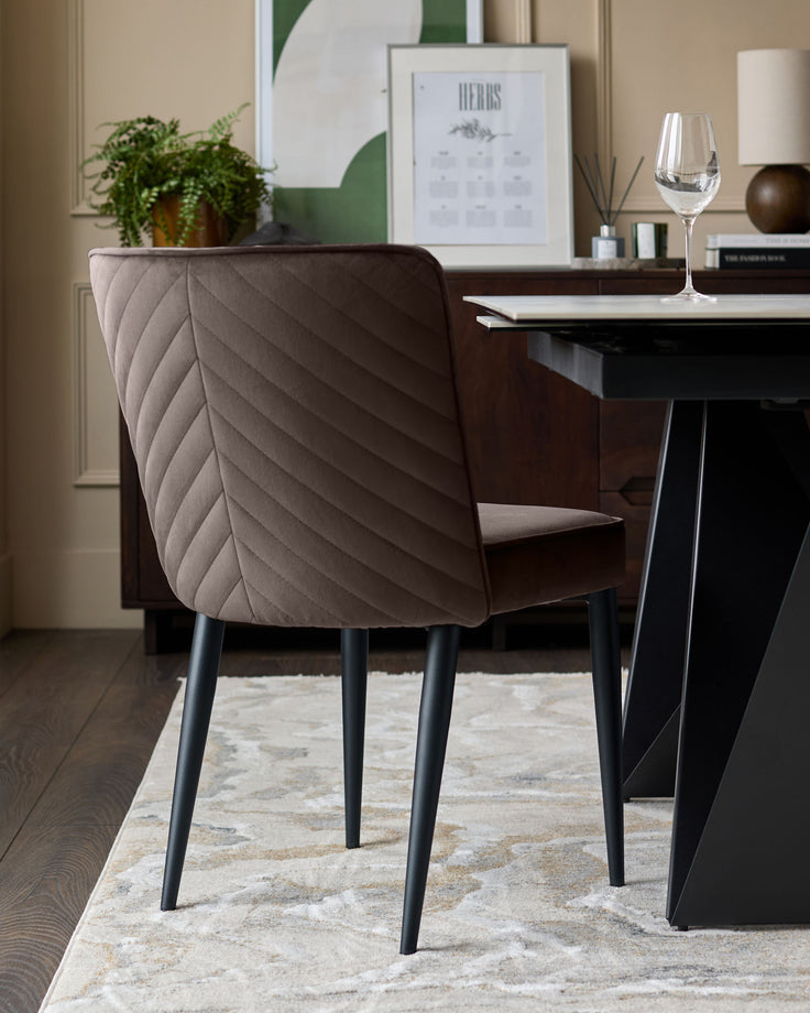 Mocha velvet dining chair with quilted backrest and black metal legs, shown in a styled dining room setting.
