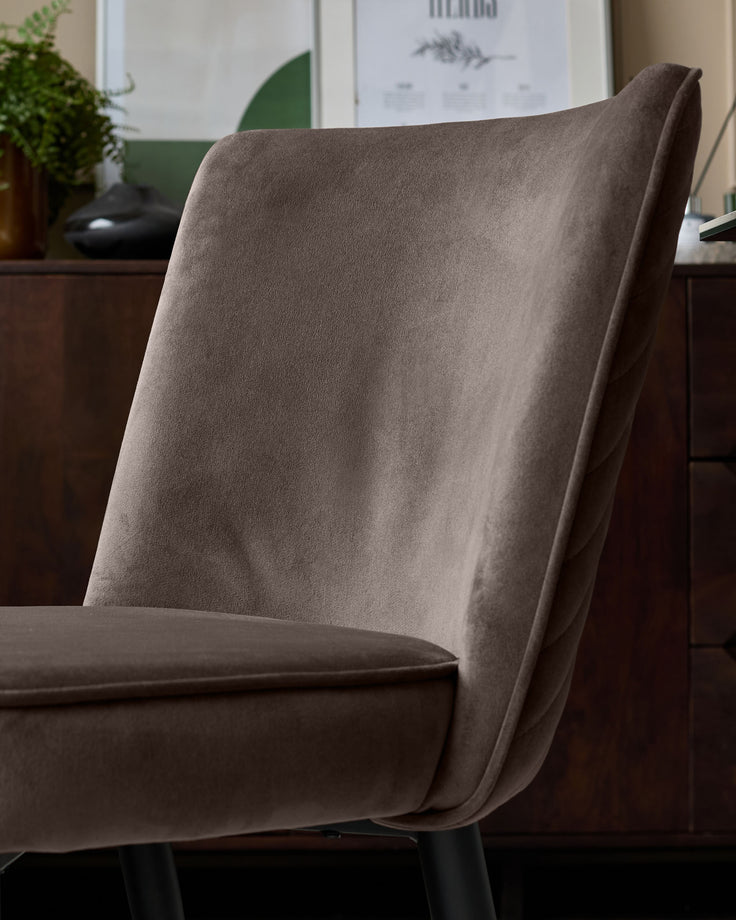 Serena velvet dining chair in mocha, shown at a side angle highlighting its curved backrest and seat upholstery with metal legs.